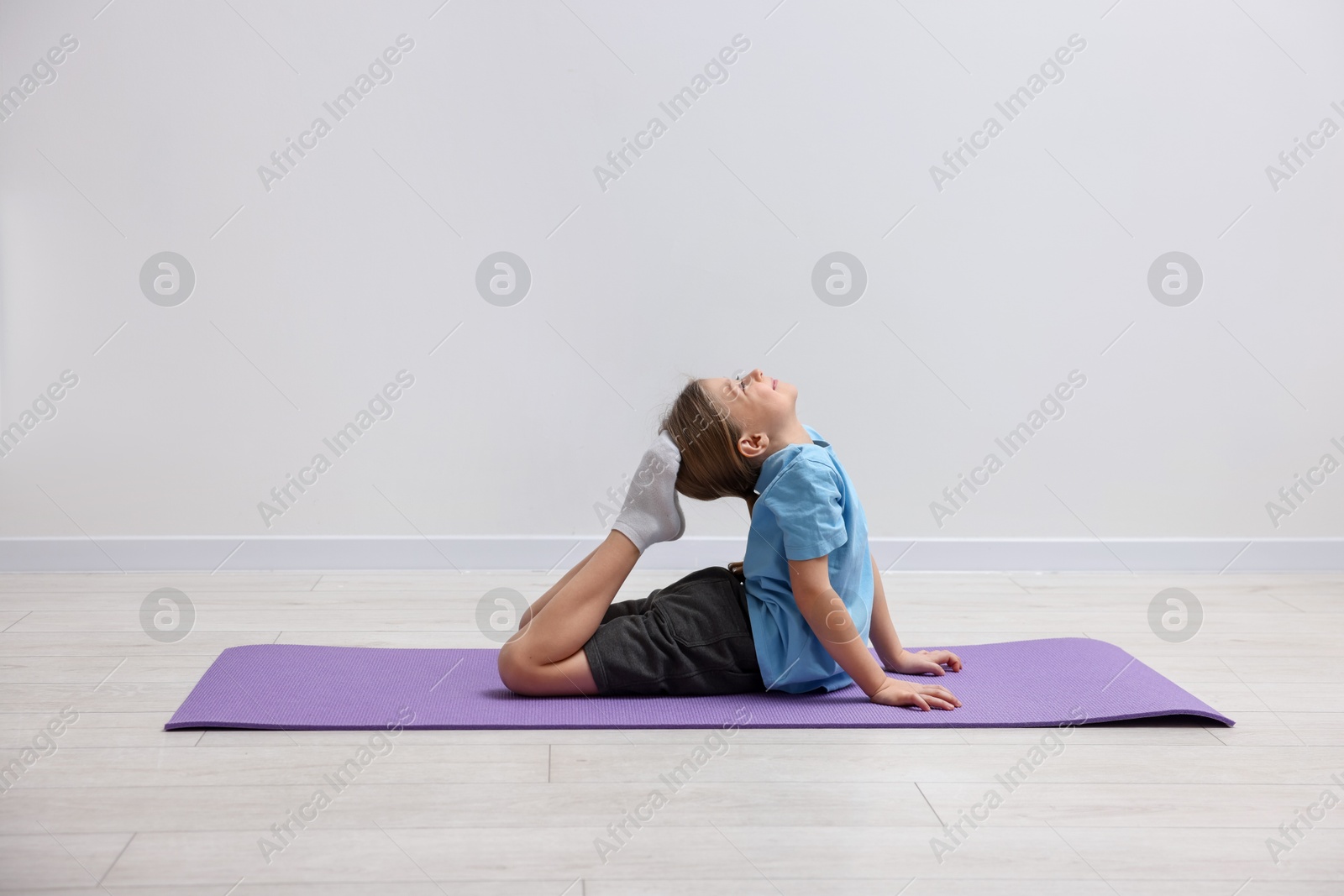 Photo of Cute little girl exercising on fitness mat indoors