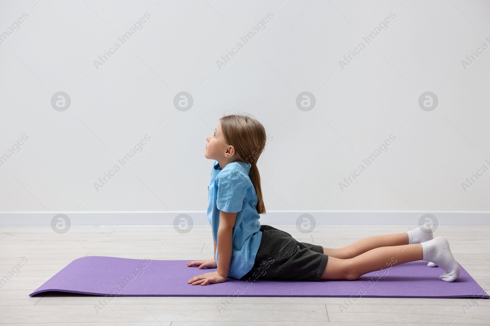 Photo of Cute little girl exercising on fitness mat indoors