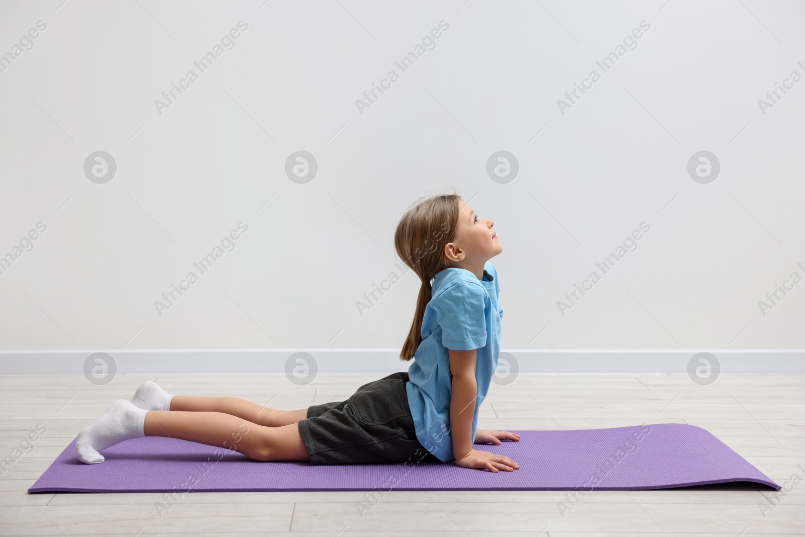 Photo of Cute little girl exercising on fitness mat indoors