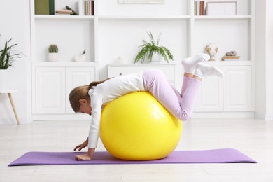 Photo of Cute little girl with fitness ball indoors