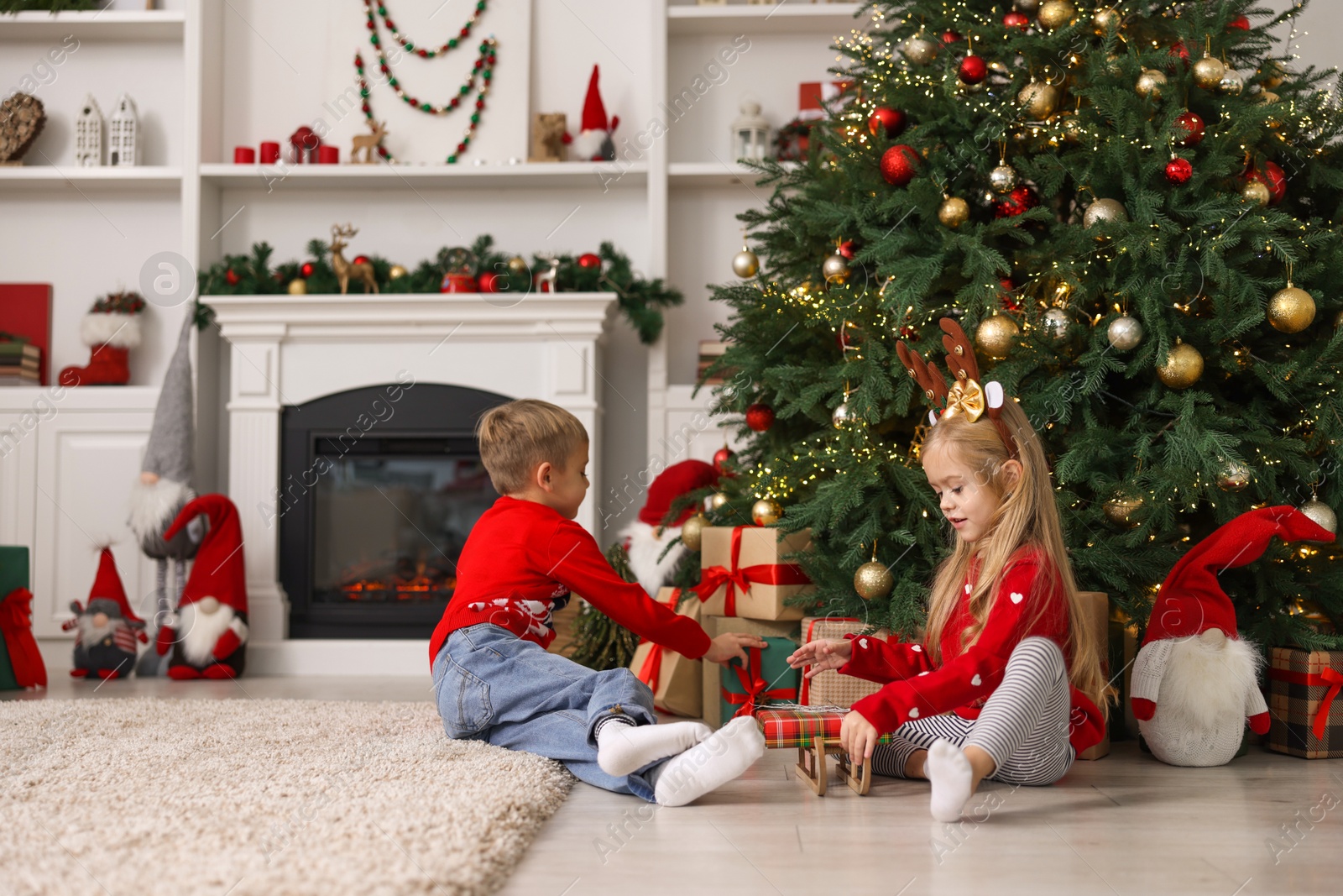 Photo of Little children with gifts near Christmas tree at home. Space for text