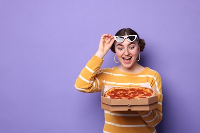 Photo of Surprised woman with delicious pizza on violet background, space for text