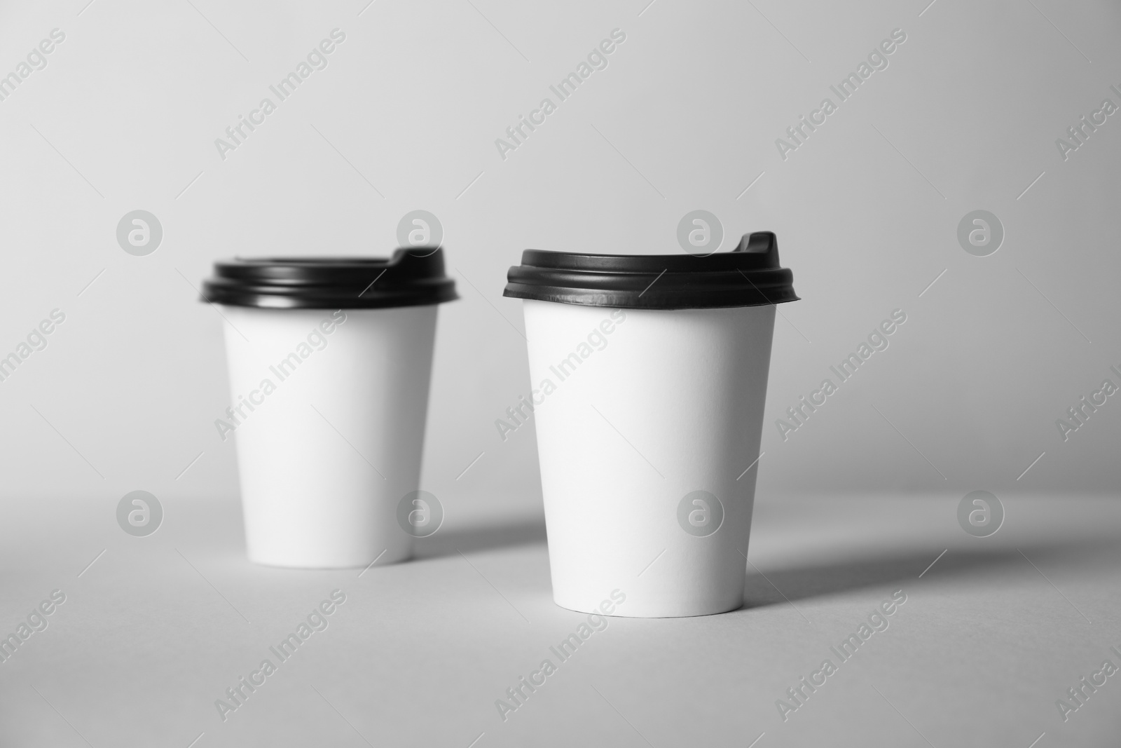 Paper cups with lids on grey background. Mockup for design Photo of Paper cups with lids on grey background. Mockup for design