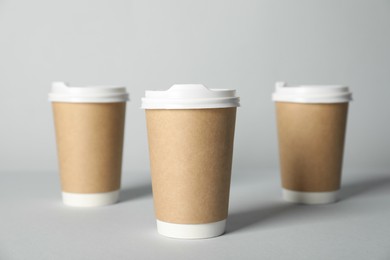 Photo of Paper cups with lids on grey background, selective focus. Mockup for design
