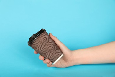Photo of Woman holding paper cup on light blue background, closeup. Mockup for design