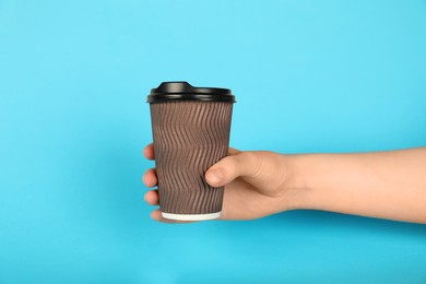 Photo of Woman holding paper cup on light blue background, closeup. Mockup for design