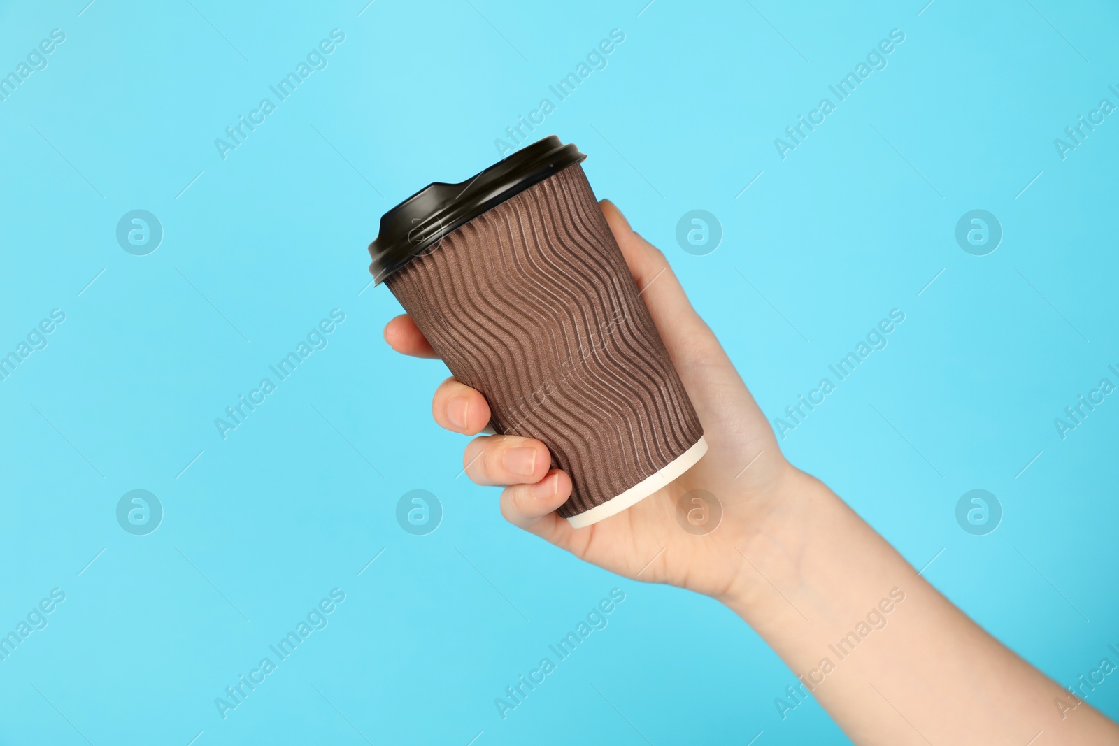 Woman holding paper cup on light blue background, closeup. Mockup for design Photo of Woman holding paper cup on light blue background, closeup. Mockup for design