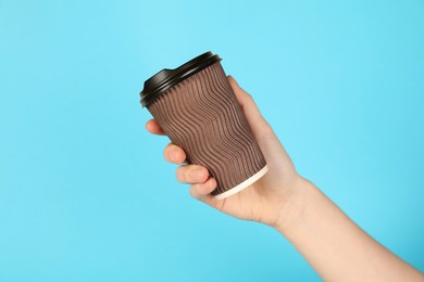 Photo of Woman holding paper cup on light blue background, closeup. Mockup for design