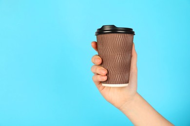 Photo of Woman holding paper cup on light blue background, closeup. Mockup for design
