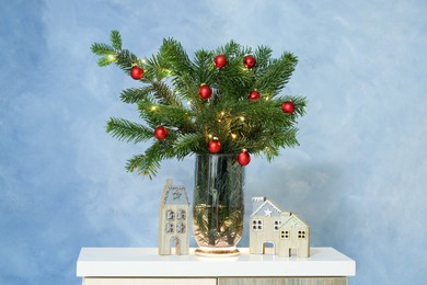 Photo of Beautiful decorated fir tree branches on white table near blue wall. Christmas season