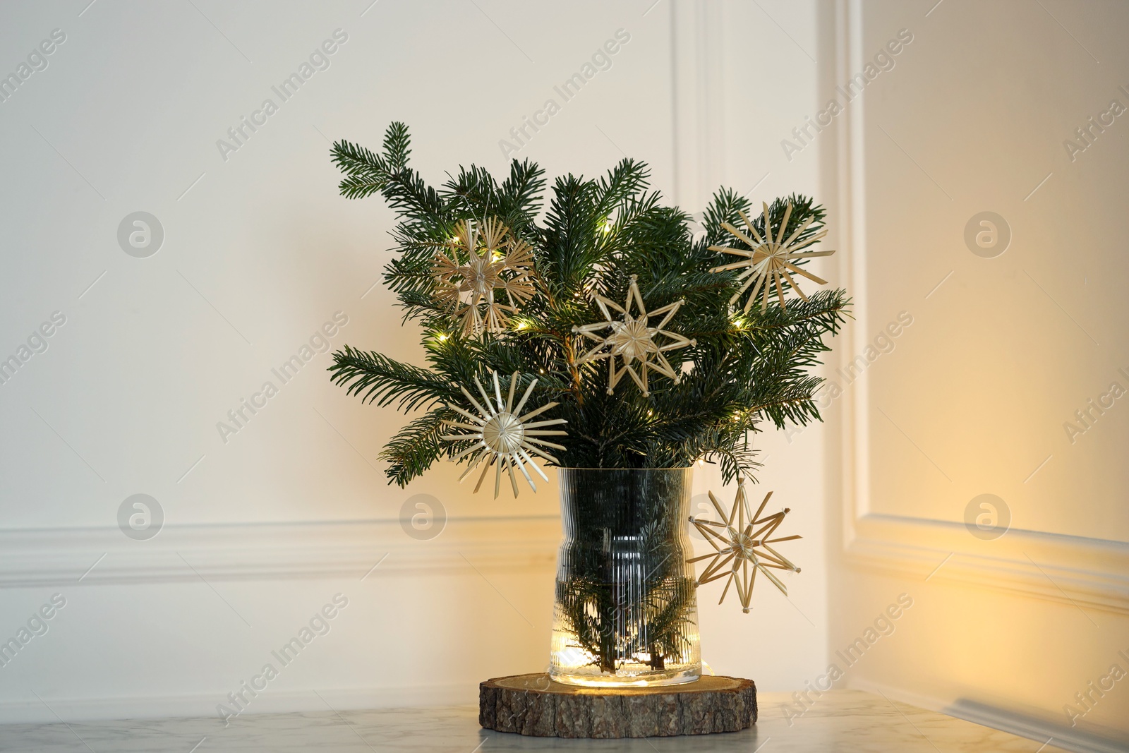 Photo of Beautiful decorated fir tree branches on table near white wall. Christmas season