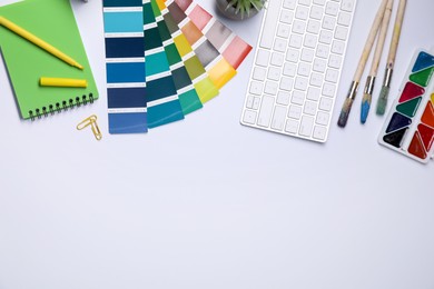 Photo of Designer's workplace with keyboard and stationery on light background, flat lay. Space for text