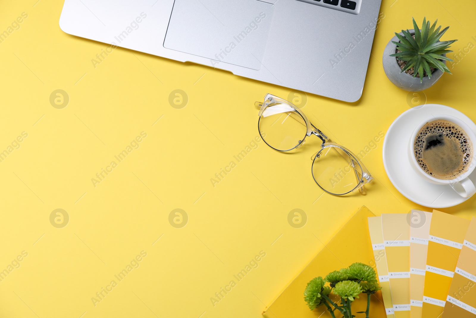 Photo of Designer's workplace with laptop, stationery and cup of coffee on yellow background, flat lay. Space for text