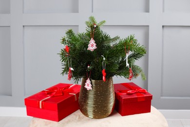 Photo of Beautiful decorated fir tree branches and Christmas gifts on pouf indoors