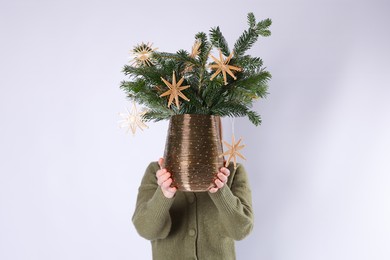 Photo of Woman holding beautiful Christmas composition of decorated fir tree branches on light background