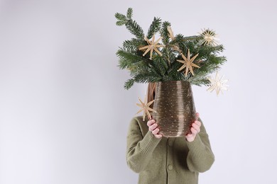 Photo of Woman holding beautiful Christmas composition of decorated fir tree branches on light background. Space for text