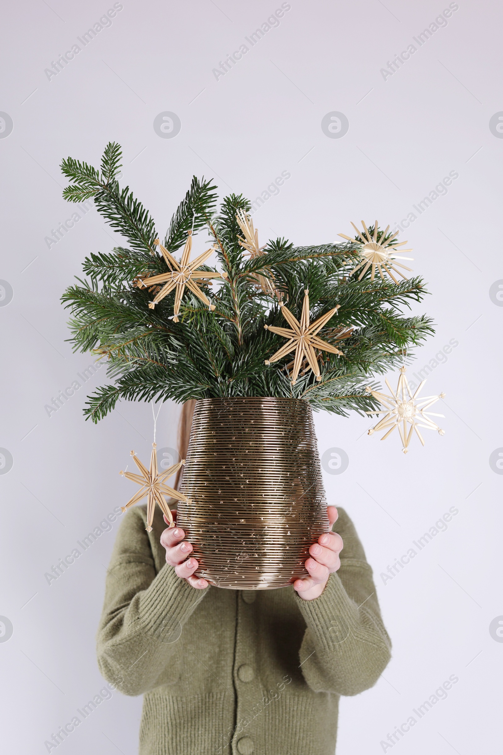 Photo of Woman holding beautiful Christmas composition of decorated fir tree branches on light background