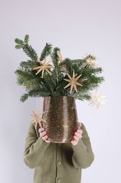 Photo of Woman holding beautiful Christmas composition of decorated fir tree branches on light background