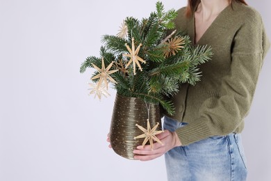 Photo of Woman holding beautiful Christmas composition of decorated fir tree branches on light background, closeup. Space for text