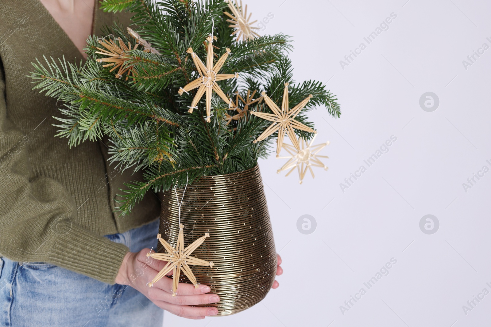 Photo of Woman holding beautiful Christmas composition of decorated fir tree branches on light background, closeup. Space for text