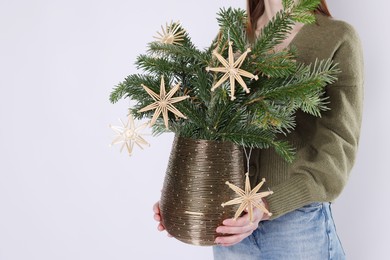 Photo of Woman holding beautiful Christmas composition of decorated fir tree branches on light background, closeup. Space for text