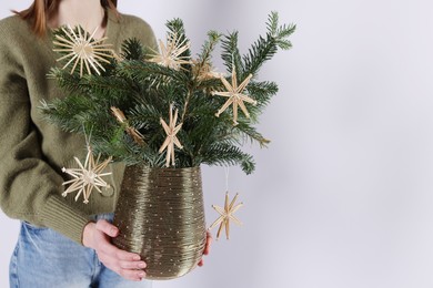 Photo of Woman holding beautiful Christmas composition of decorated fir tree branches on light background, closeup. Space for text