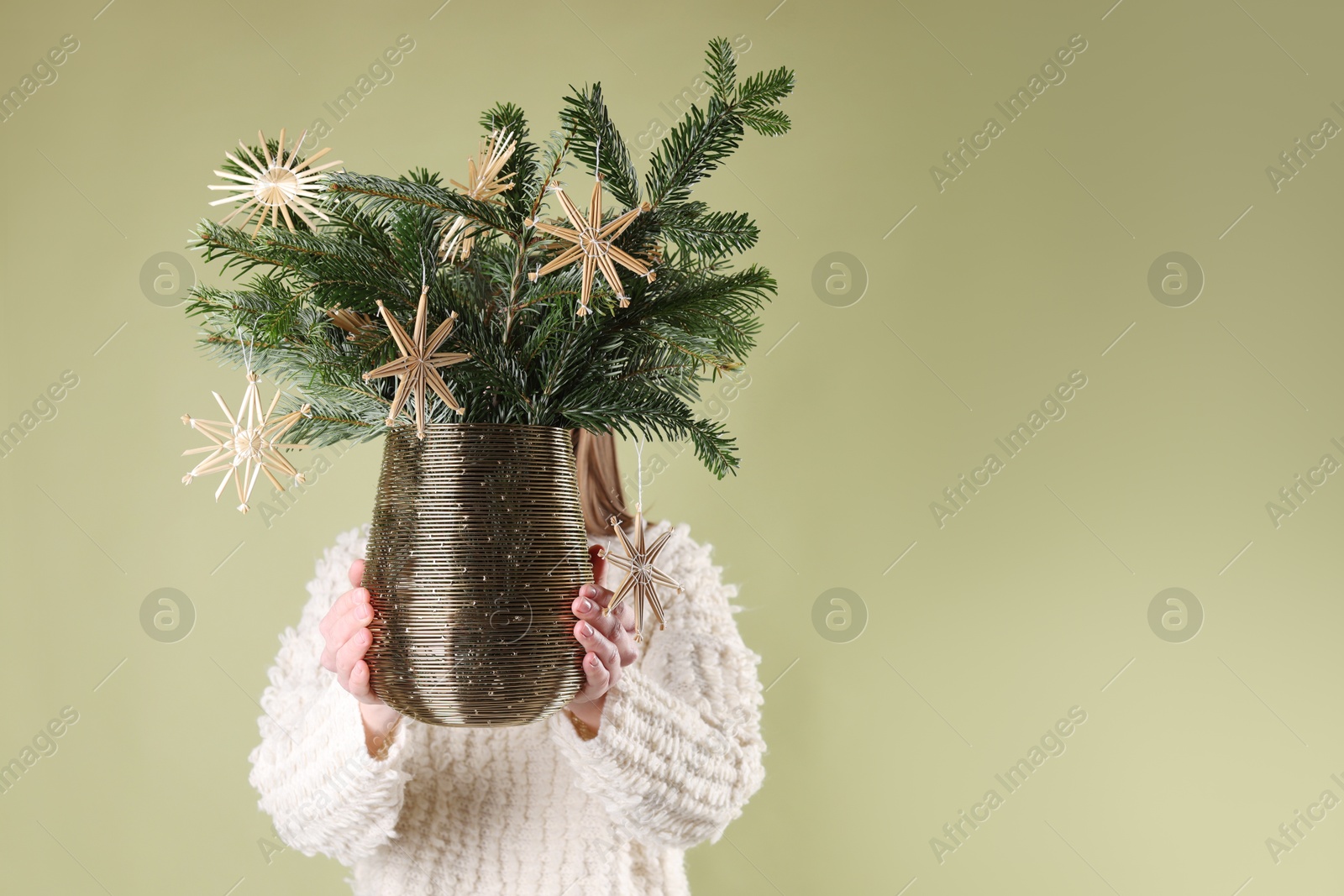 Photo of Woman holding beautiful Christmas composition of decorated fir tree branches on light green background. Space for text