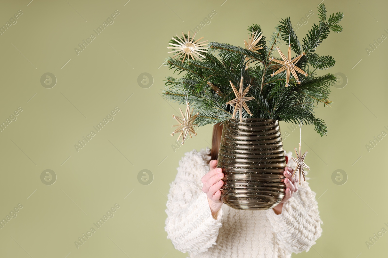 Photo of Woman holding beautiful Christmas composition of decorated fir tree branches on light green background. Space for text