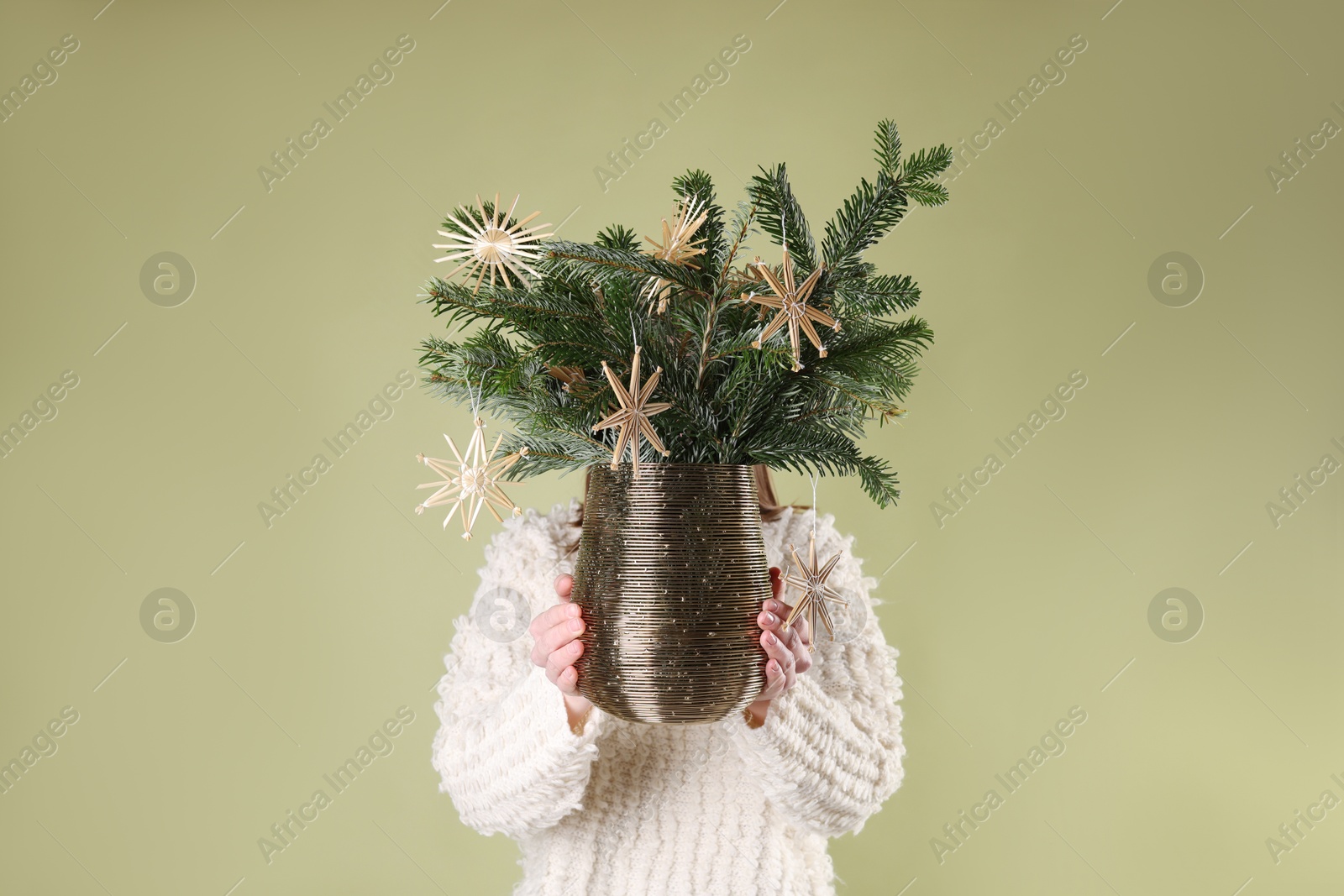 Photo of Woman holding beautiful Christmas composition of decorated fir tree branches on light green background