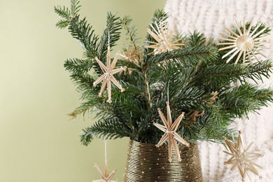 Photo of Woman holding beautiful Christmas composition of decorated fir tree branches on light green background, closeup