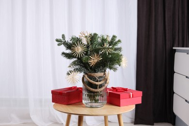 Photo of Beautiful composition of decorated fir tree branches and Christmas gifts on table indoors