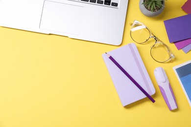 Photo of Designer's workplace. Flat lay composition with stationery and laptop on yellow background, space for text