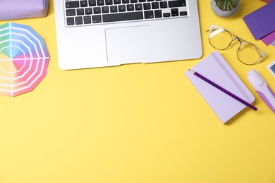 Photo of Designer's workplace. Flat lay composition with stationery and laptop on yellow background, space for text