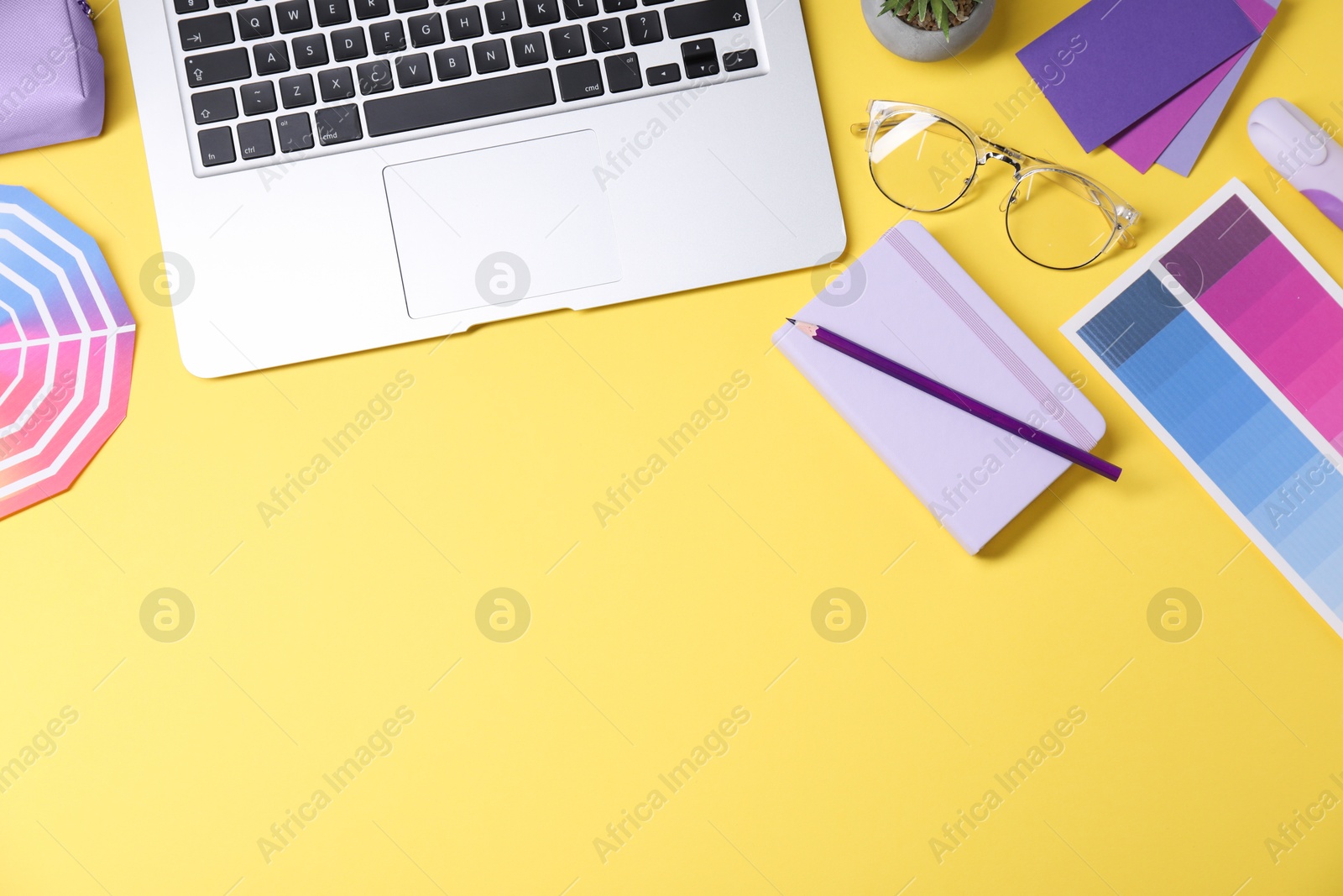 Photo of Designer's workplace. Flat lay composition with stationery and laptop on yellow background, space for text