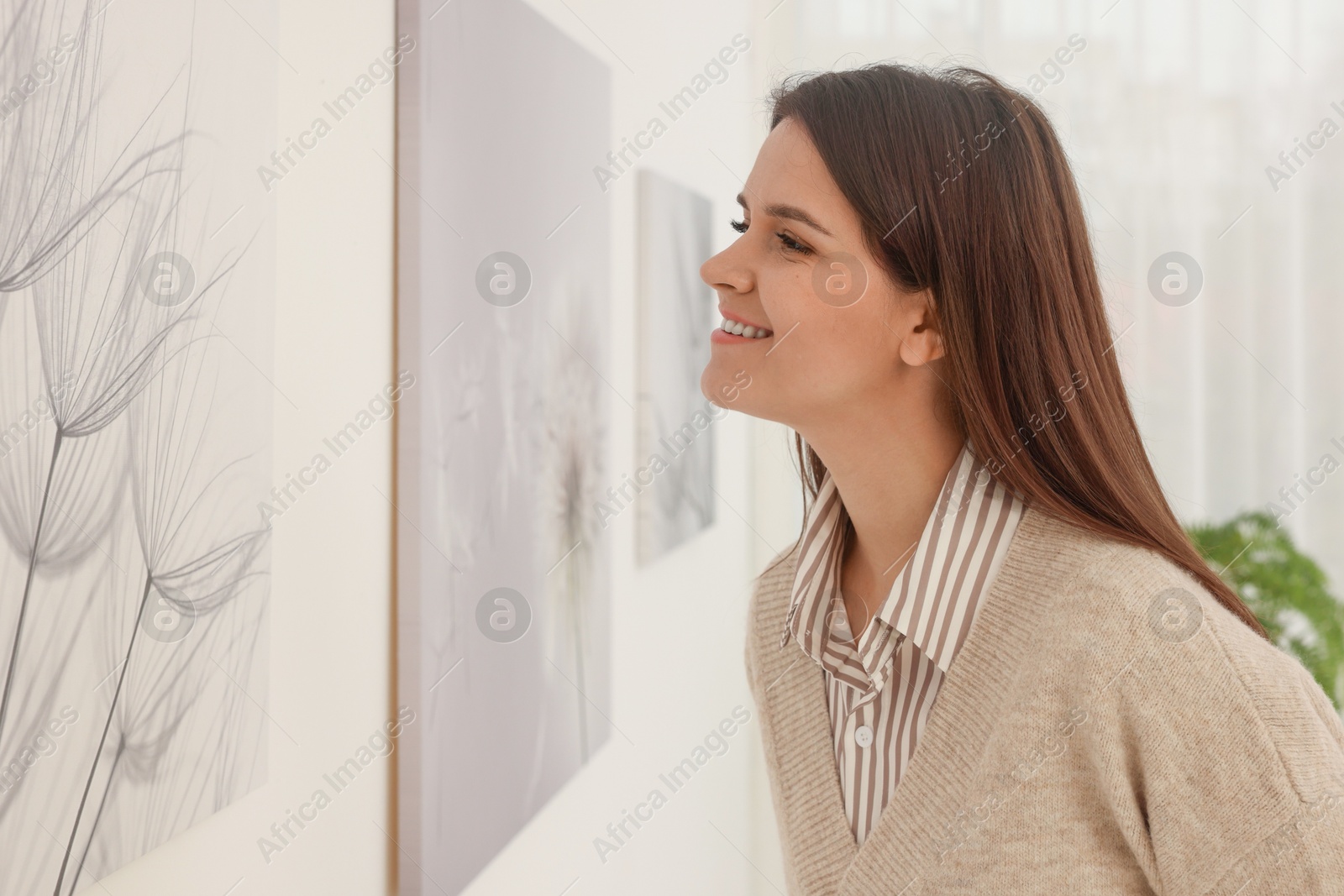 Photo of Woman studying beautiful artwork in modern gallery