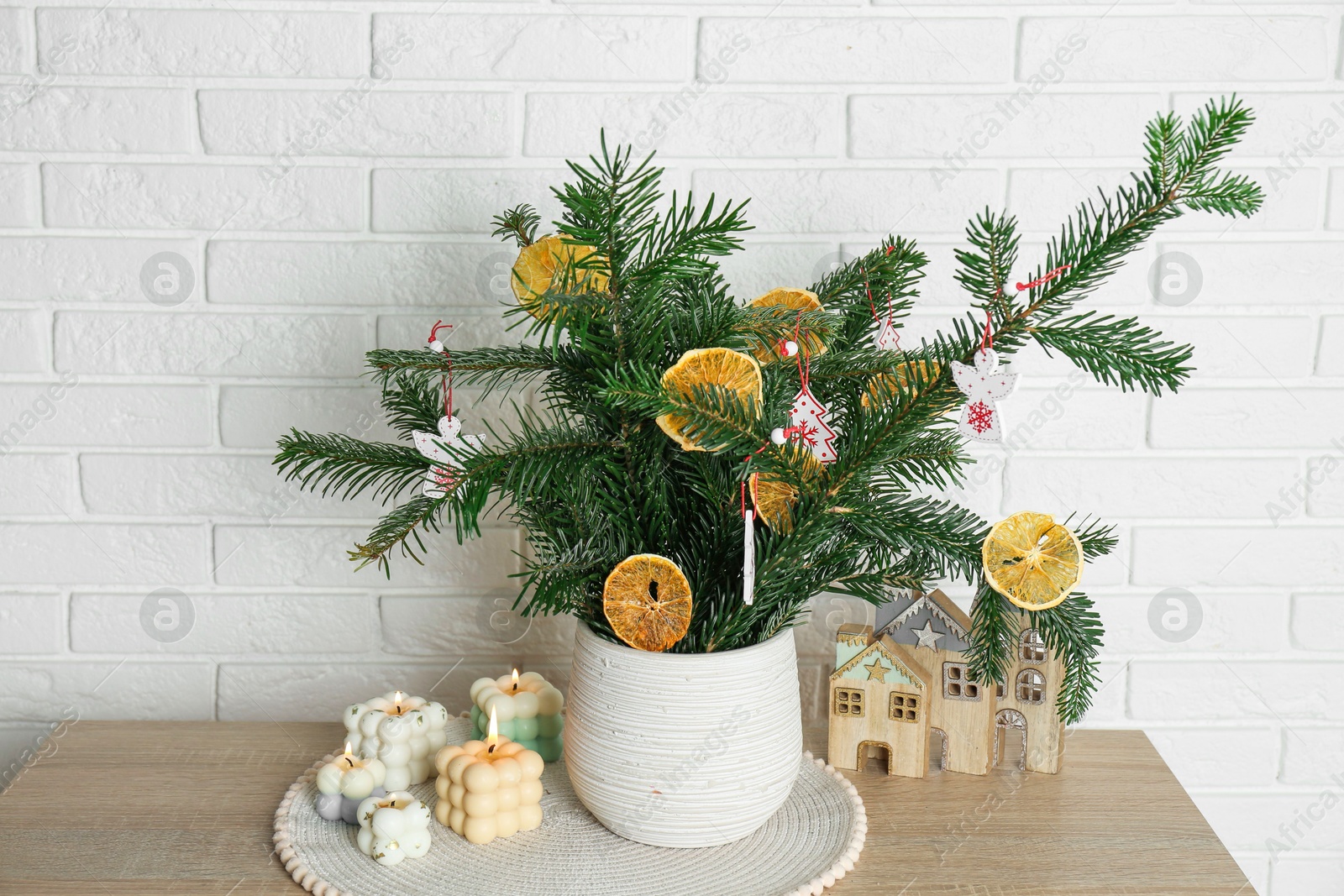 Photo of Beautiful Christmas composition of decorated fir tree branches on wooden table near white brick wall