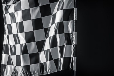 Photo of One racing checkered flag on black background, space for text