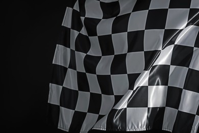 Photo of One racing checkered flag on black background, closeup