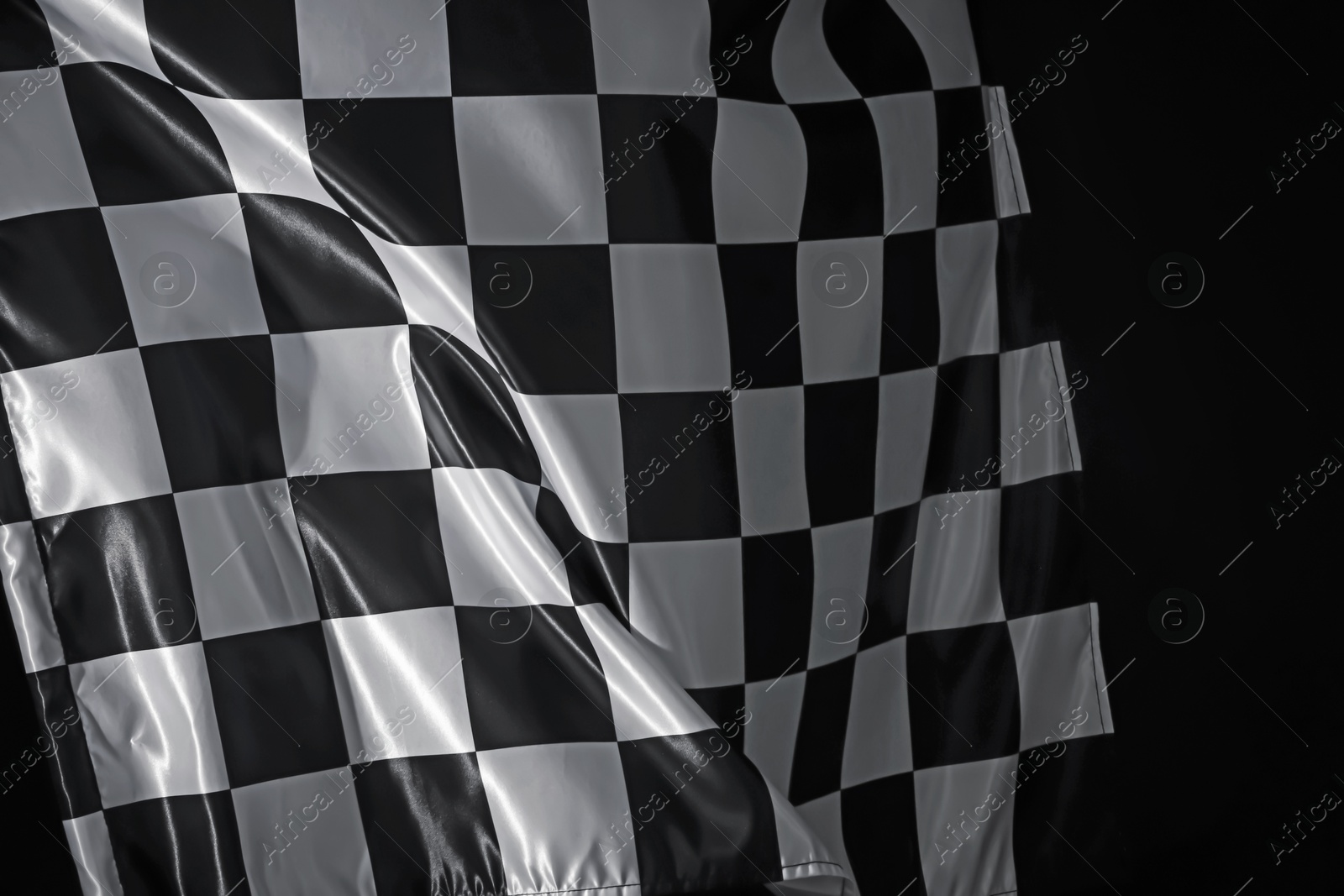 Photo of One racing checkered flag on black background, closeup