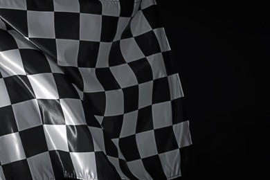 Photo of One racing checkered flag on black background, space for text