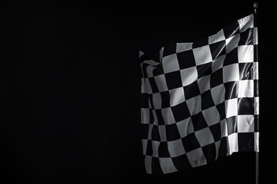 Photo of One racing checkered flag on black background, space for text