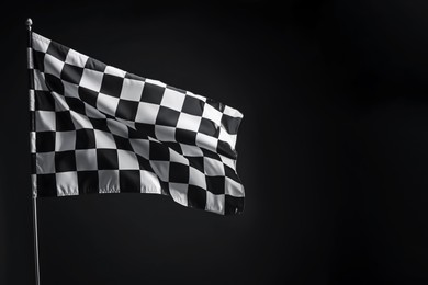 Photo of One racing checkered flag on black background, space for text