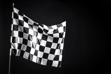 Photo of One racing checkered flag on black background, space for text