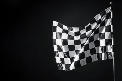 Photo of One racing checkered flag on black background, space for text