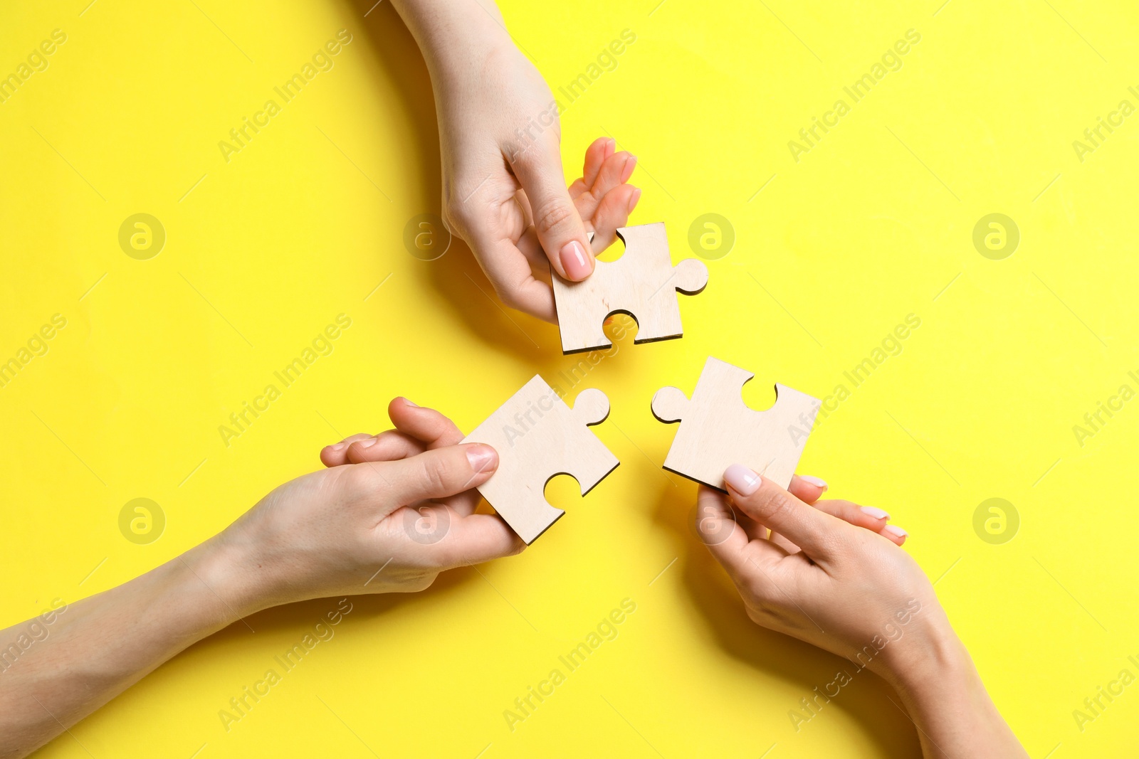 Photo of Business strategy and teamwork concept. Partners with different puzzle pieces on yellow background, top view