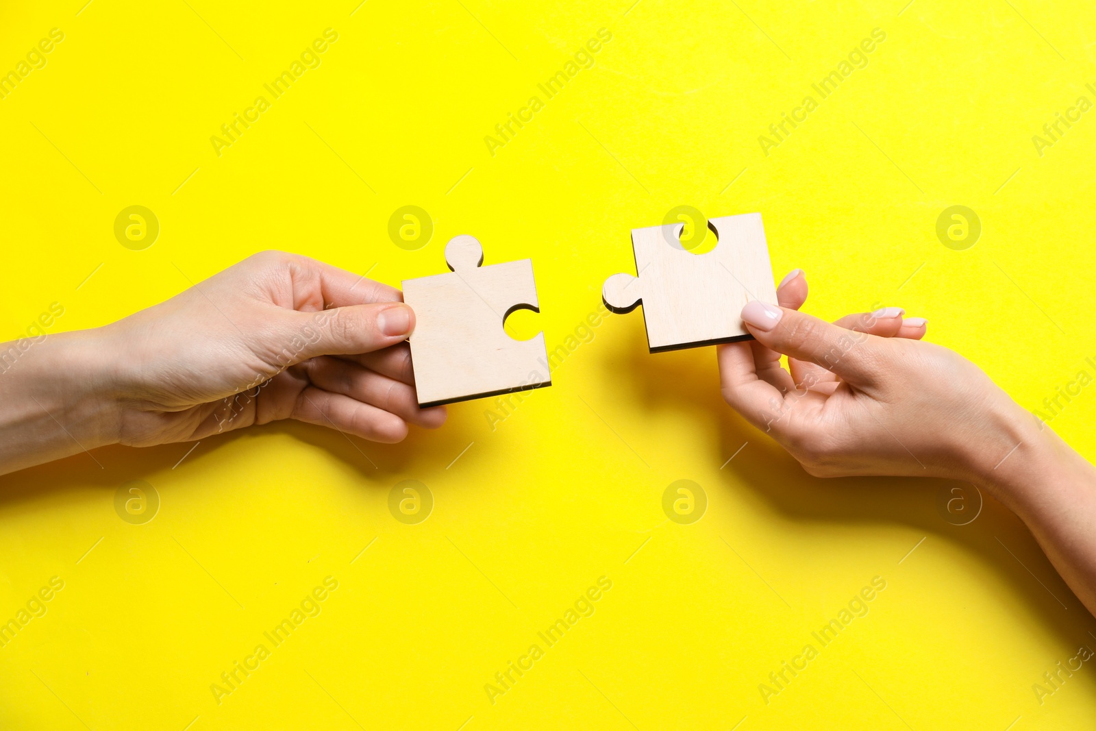 Photo of Business strategy and teamwork concept. Partners putting puzzle pieces together on yellow background, top view