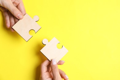 Photo of Business strategy and teamwork concept. Partners putting puzzle pieces together on yellow background, top view with space for text