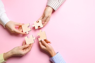 Photo of Business strategy and teamwork concept. Group of businesspeople putting puzzle pieces together on pink background, top view with space for text