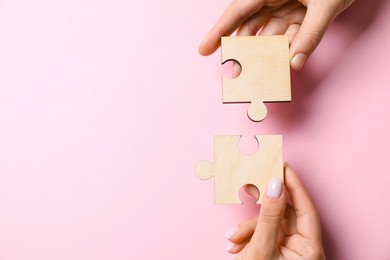 Photo of Business strategy and teamwork concept. Partners putting puzzle pieces together on pink background, top view with space for text