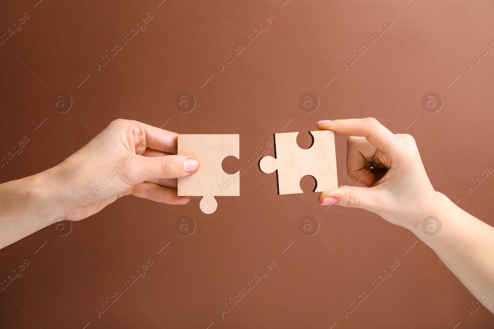 Photo of Business strategy and teamwork concept. Partners putting puzzle pieces together on brown background, closeup